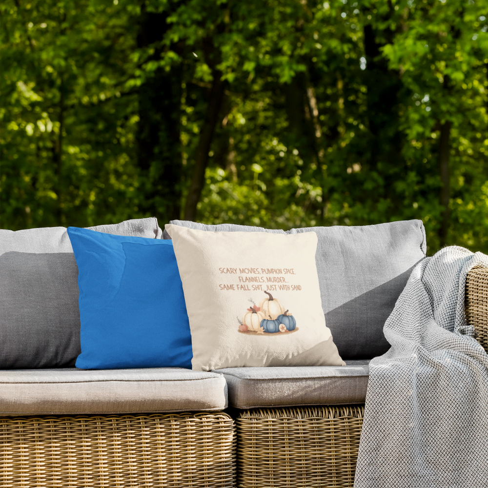 Outdoor setting with a wicker bench featuring cushions and a blanket against a green foliage background.