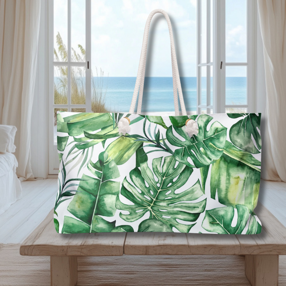Tote bag with tropical leaf pattern on a wooden table with a beach view in the background