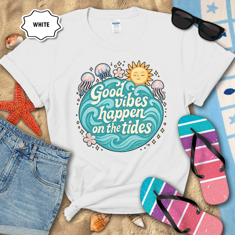 White t-shirt with 'Good vibes happen on the tides' design, surrounded by beach accessories.