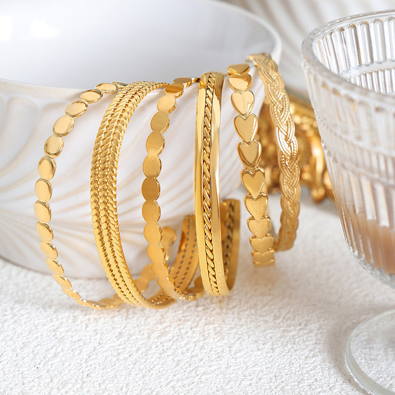 Gold bracelets with various designs on a white surface