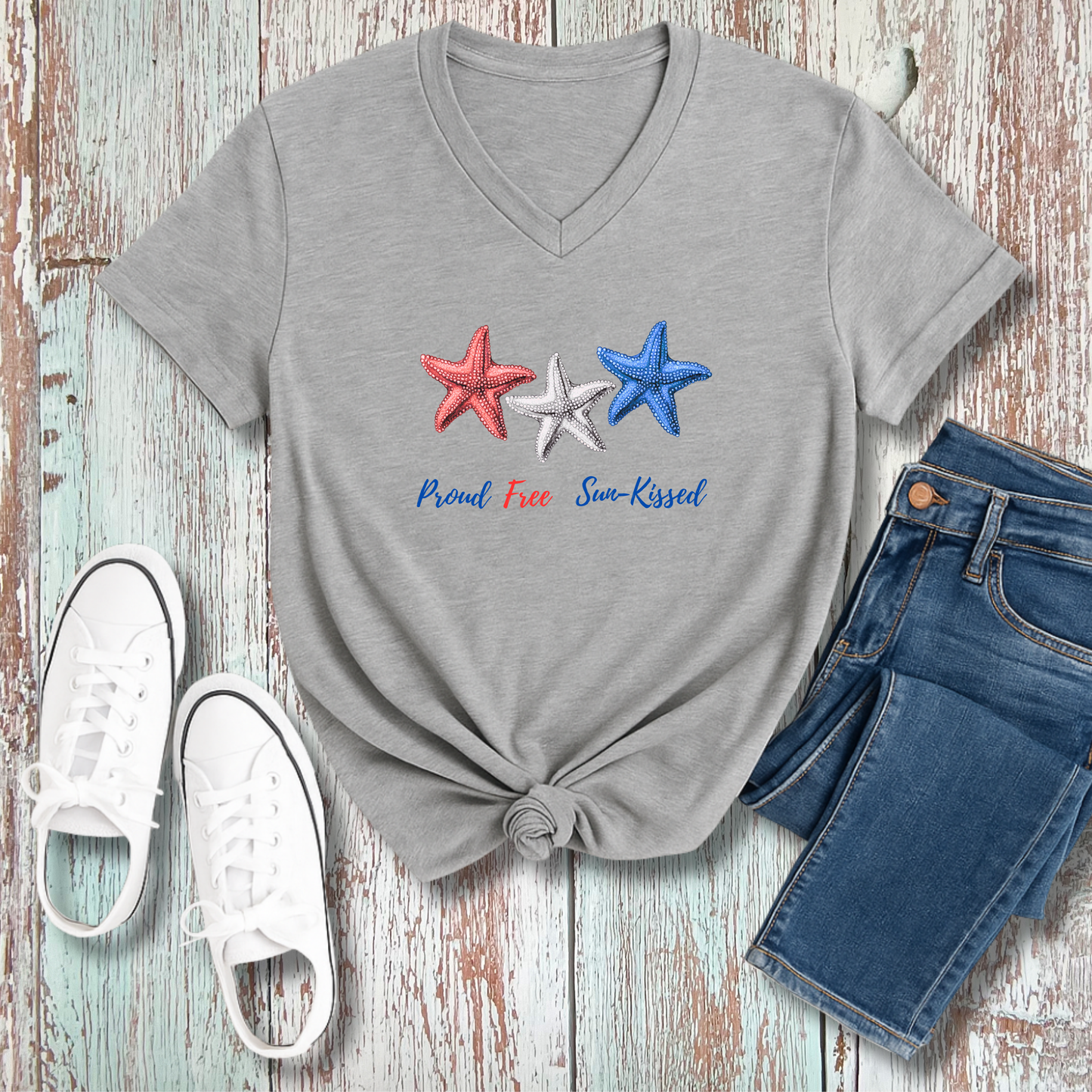 Gray t-shirt with star design and text, paired with jeans and sneakers on a wooden surface