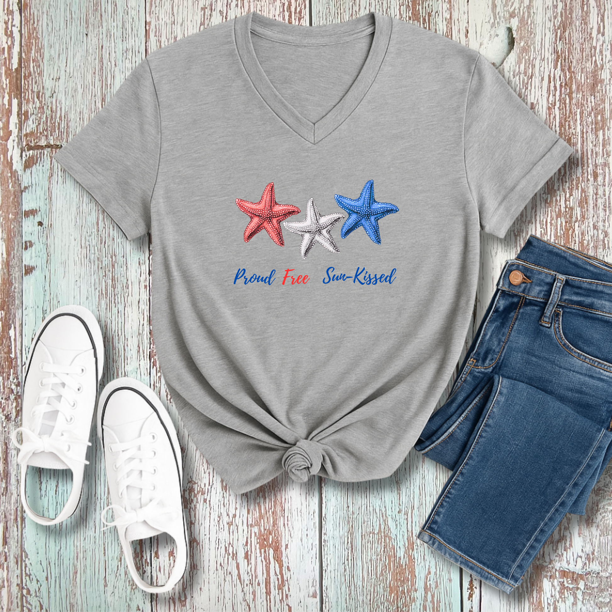 Gray t-shirt with star design and text, paired with jeans and sneakers on a wooden surface