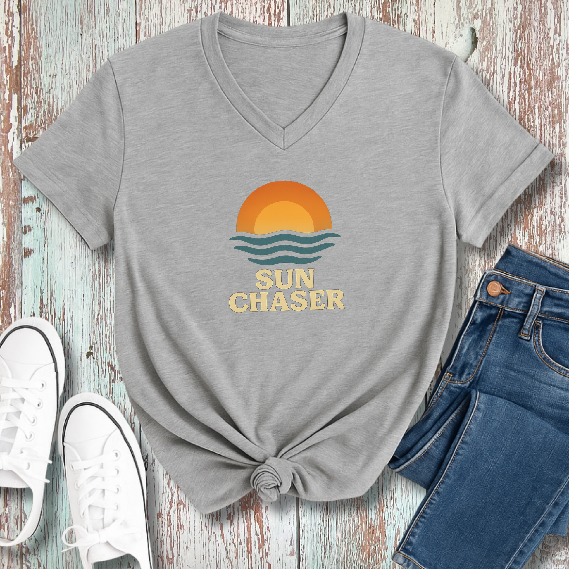 Gray t-shirt with 'Sun Chaser' design on a wooden surface with jeans and sneakers.
