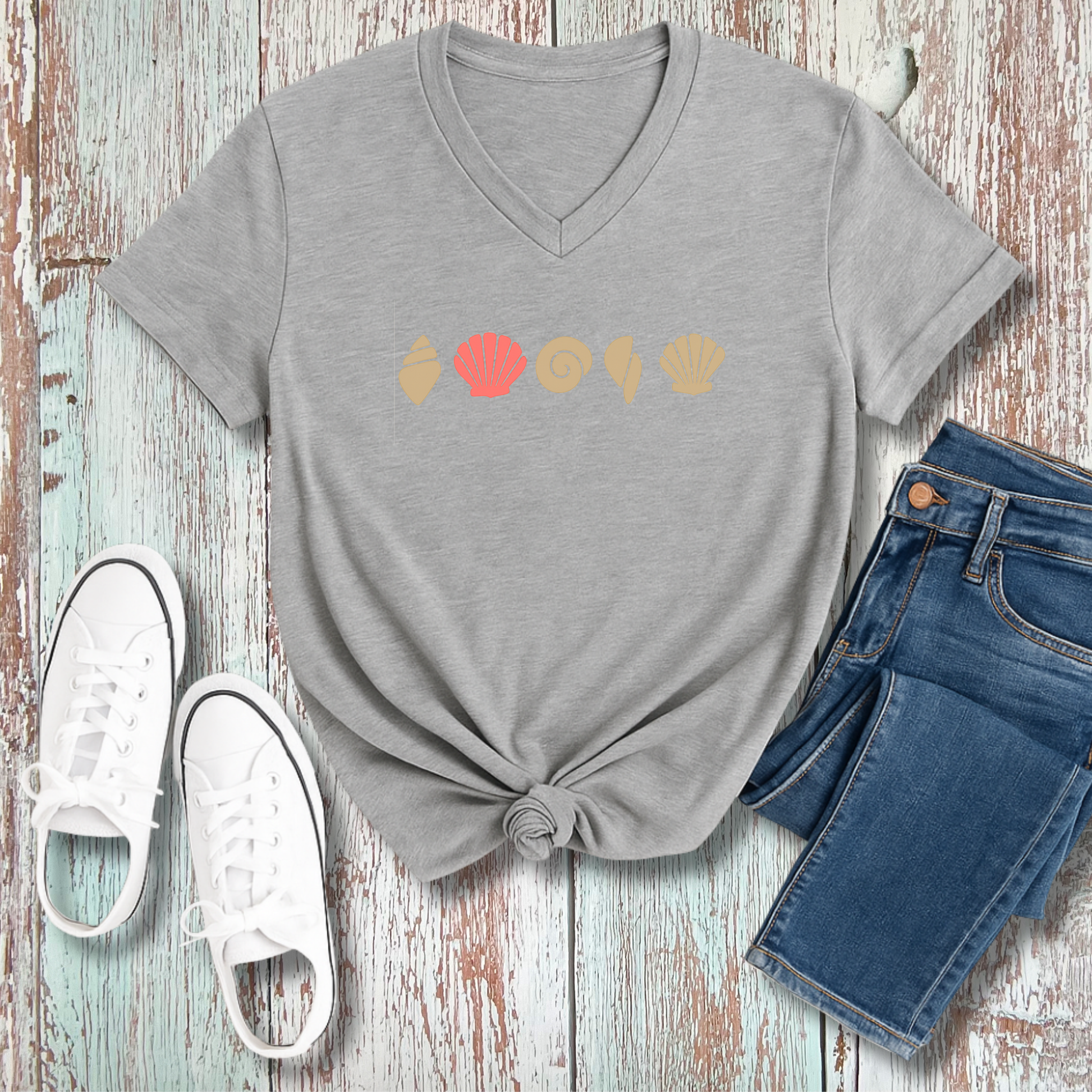 Gray t-shirt with colorful graphic, white sneakers, and blue jeans on a wooden surface
