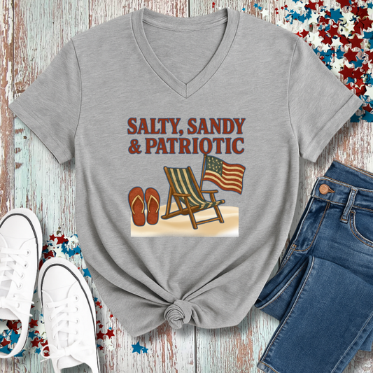 Gray t-shirt with 'Salty, Sandy & Patriotic' design featuring an American flag, beach chair, and flip-flops on a wooden surface.