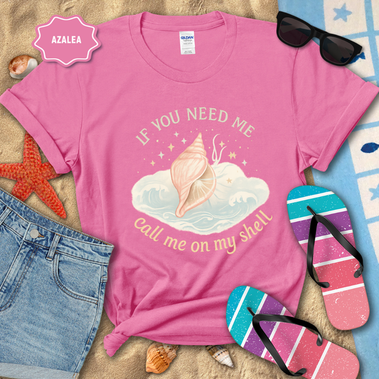 Pink t-shirt with beach-themed design and summer accessories on sand