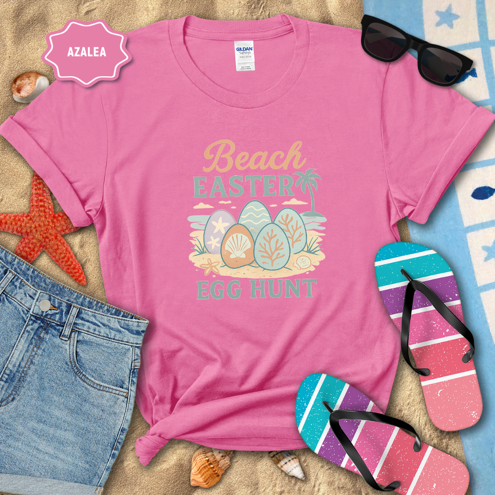 Pink t-shirt with 'Beach Easter Egg Hunt' design on a sandy background with flip-flops and sunglasses.
