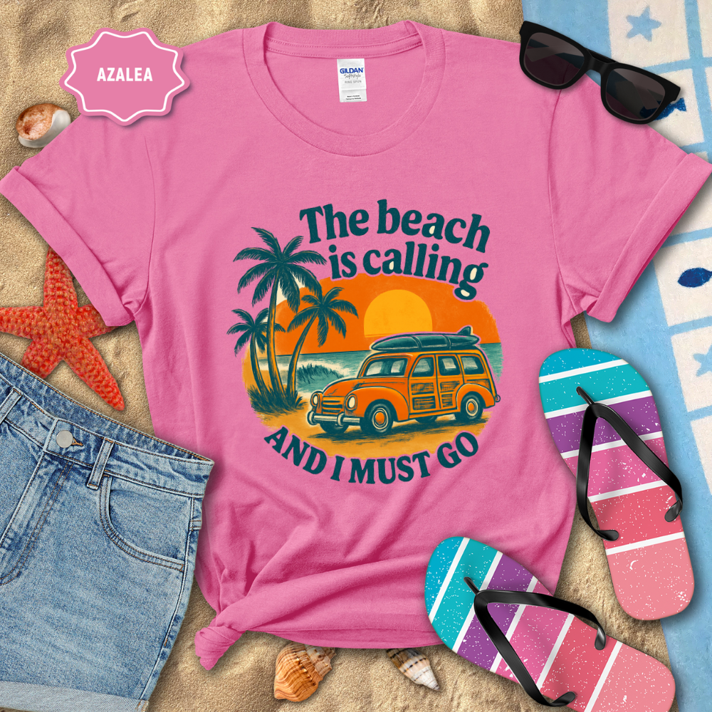 Pink t-shirt with beach-themed design and summer accessories on sand