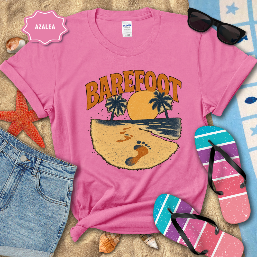 Pink t-shirt with 'Barefoot' design on a beach-themed background with sunglasses, flip-flops, and denim shorts.