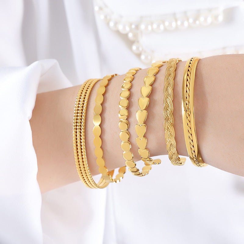 Gold bracelets on a person's wrist against a white background