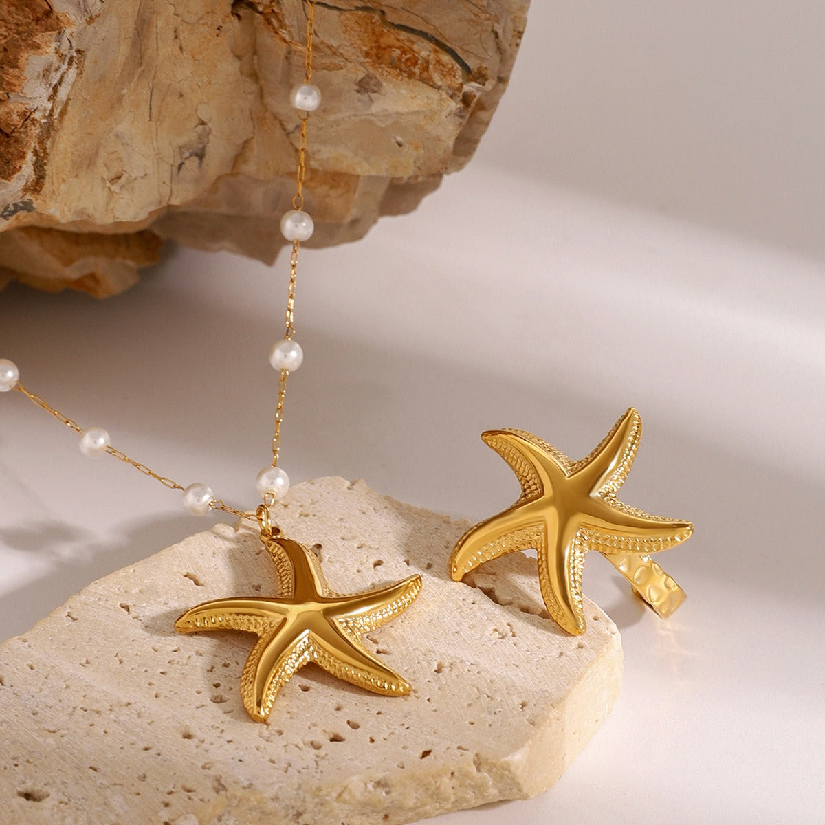 Gold starfish necklace and earrings on a stone surface
