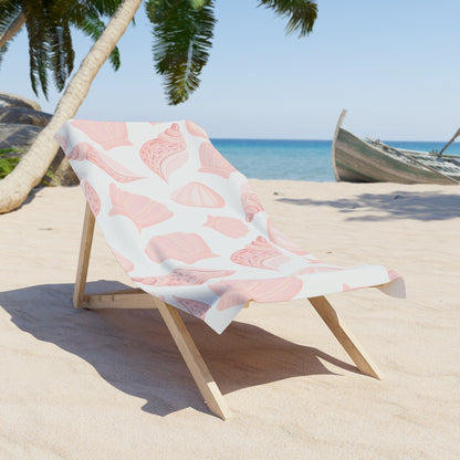White beach towel with soft pink seashell pattern on a lounge chair