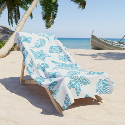 Luxurious beach towel with teal sea life pattern on a lounge chair by the ocean

