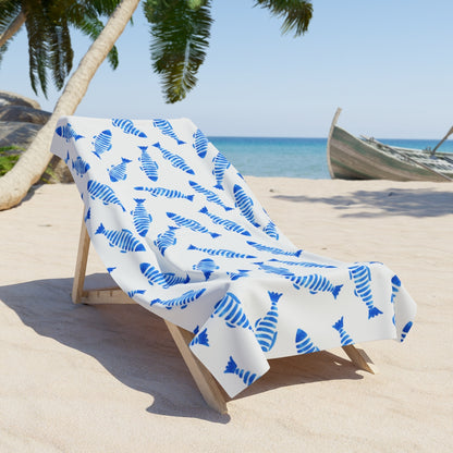 White beach towel with blue striped fish pattern on lounge chair