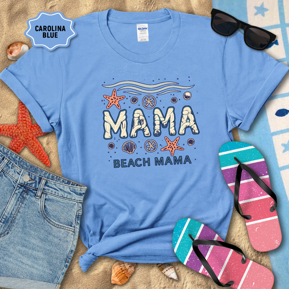 Blue t-shirt with 'Mama Beach Mama' design on sand with beach accessories.