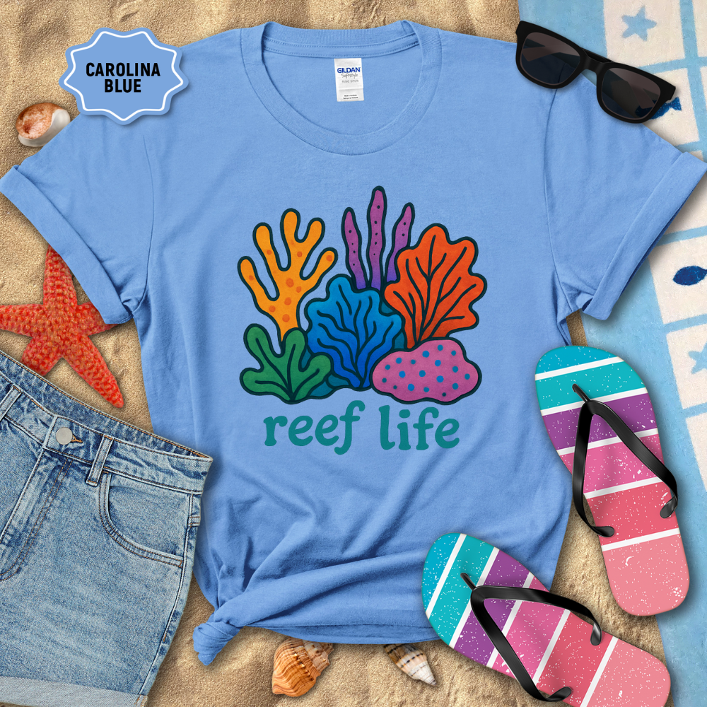 Blue t-shirt with 'reef life' design on a sandy background with beach accessories.