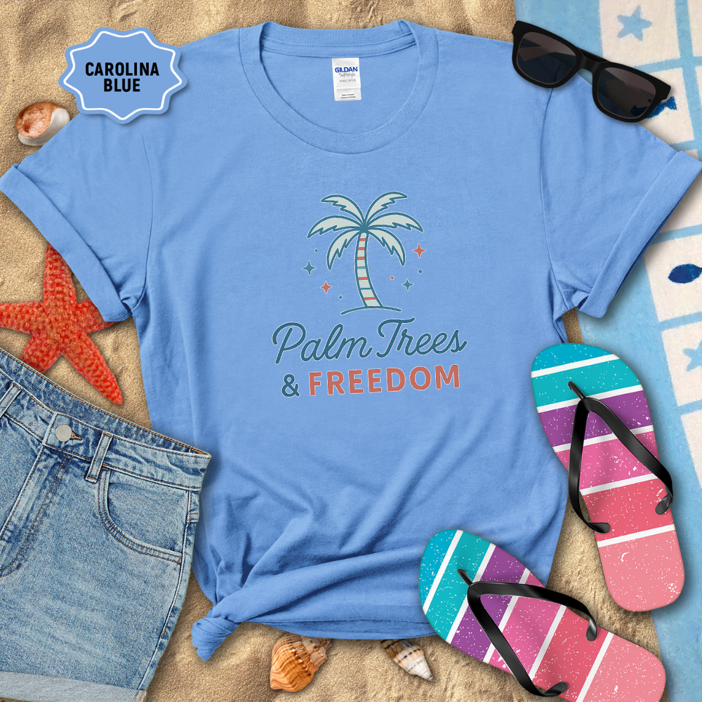 Blue t-shirt with 'Palm Trees & Freedom' design on a sandy background with beach accessories.