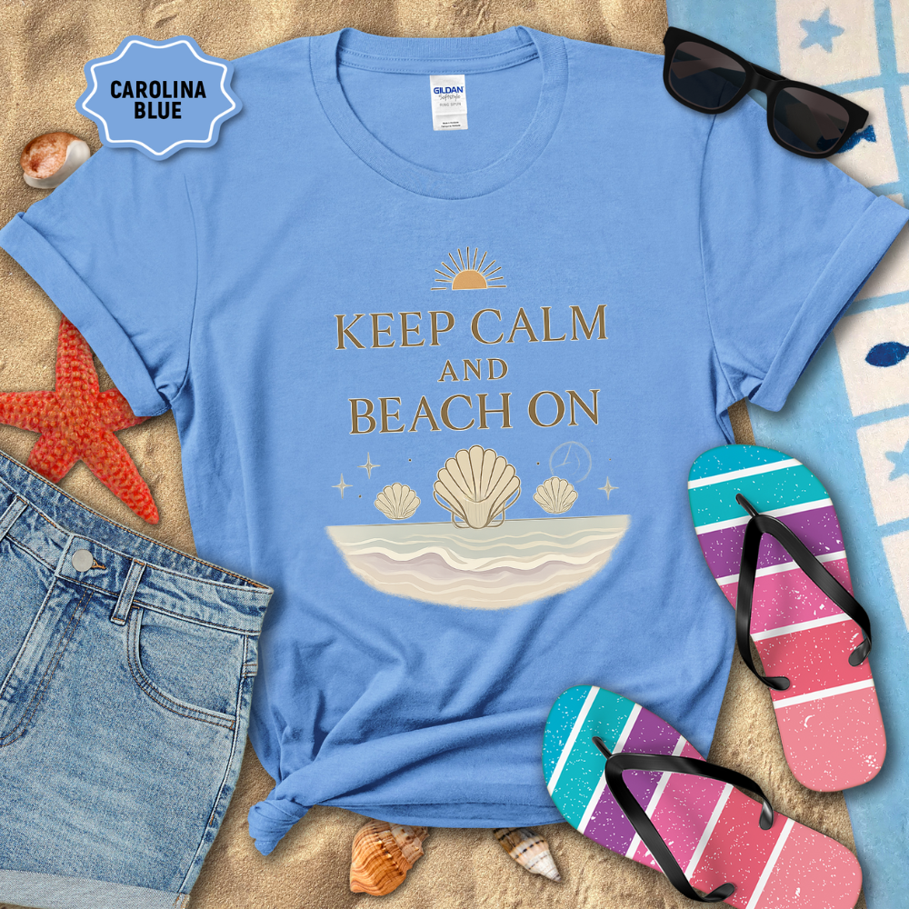 Blue t-shirt with 'Keep Calm and Beach On' design on a sandy background with beach accessories.