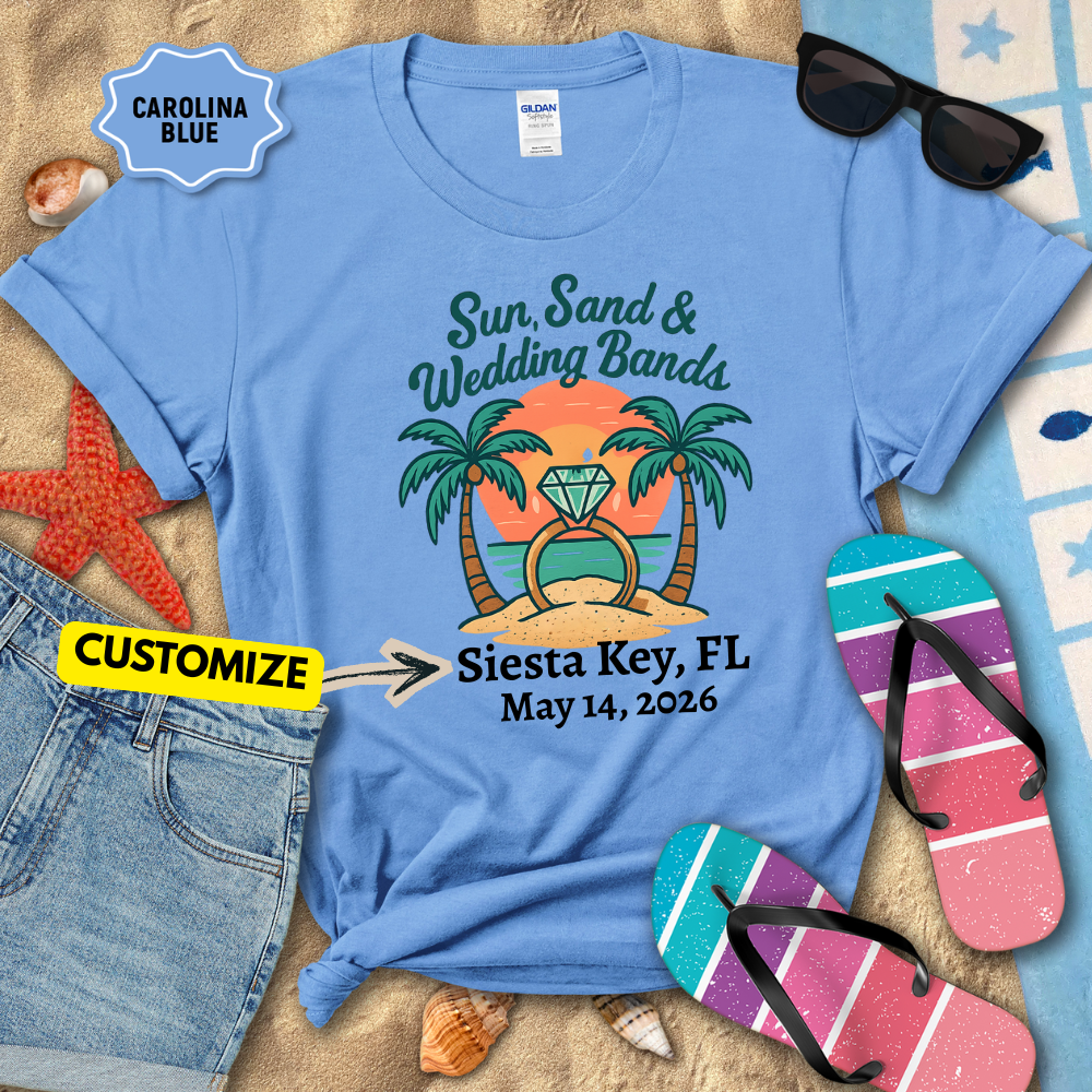 Blue t-shirt with 'Sun, Sand & Wedding Bands' design on a sandy background with flip-flops and sunglasses.