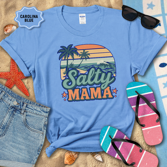 Blue t-shirt with 'Salty Mama' design on a sandy background with beach accessories.