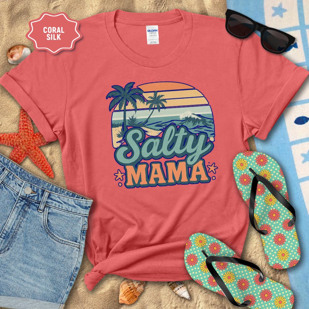 Coral t-shirt with 'Salty Mama' design on a beach-themed background with sunglasses, flip-flops, and denim shorts.