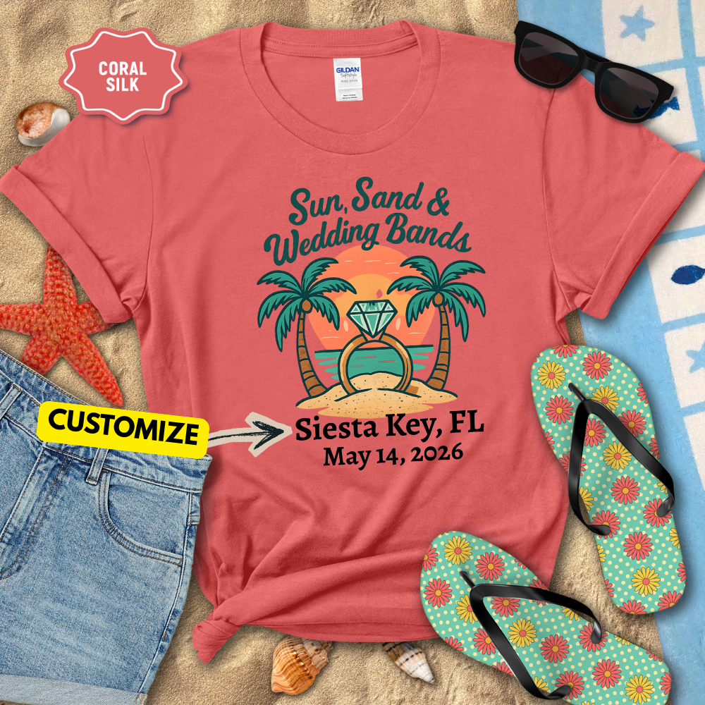 Red t-shirt with 'Sun, Sand & Wedding Bands' design on a beach setting with sunglasses, flip-flops, and sand.