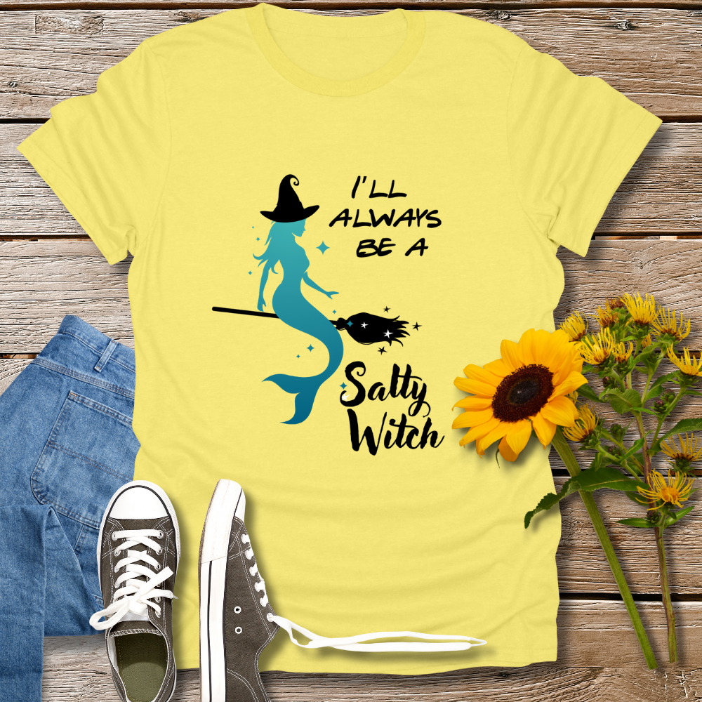 Yellow t-shirt with mermaid graphic and text on a wooden surface with jeans and sunflowers.