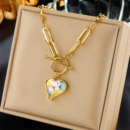 Close-up of nature-inspired 18K gold necklaces with thick chain and heart pendant


