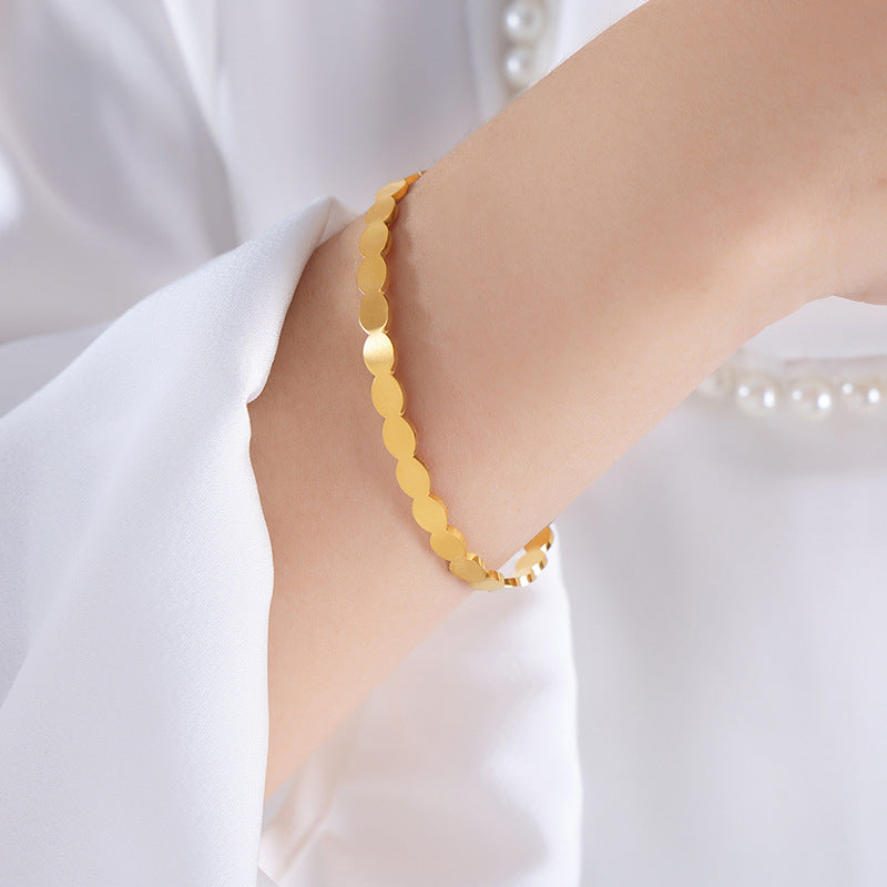 Gold bracelet on a person's wrist with a white background