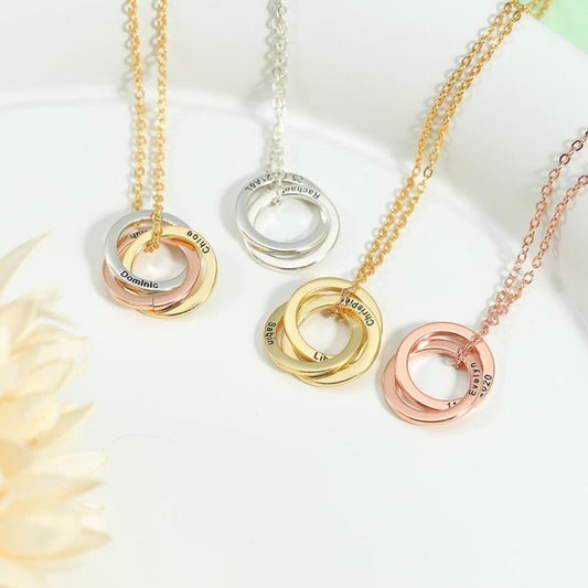 Set of gold, silver, and rose gold necklaces with interlocking rings on a white background.