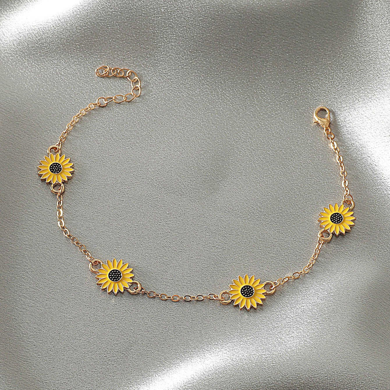 Gold bracelet with sunflower charms on a metallic surface