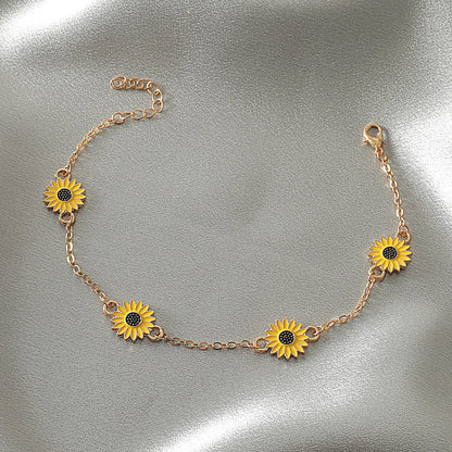 Gold bracelet with sunflower charms on a metallic surface
