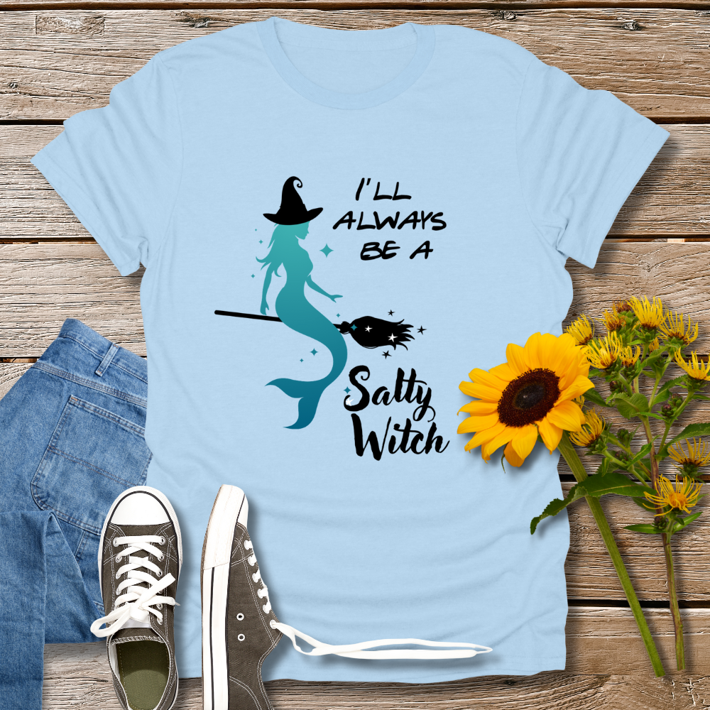 Light blue t-shirt with mermaid design and text on a wooden surface with jeans and sunflowers.