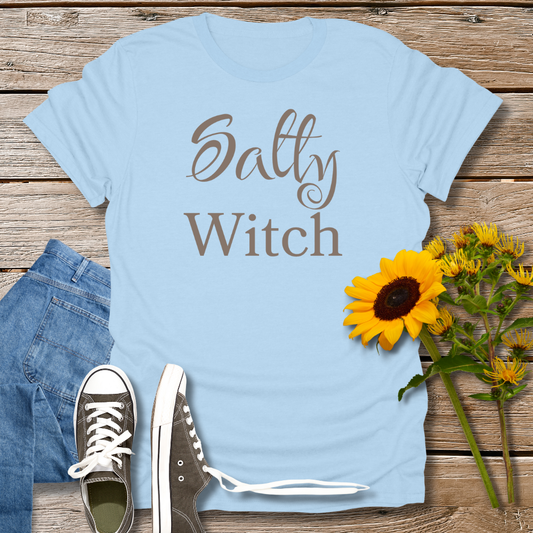 Light blue t-shirt with 'Salty Witch' text, paired with jeans and sneakers on a wooden surface.