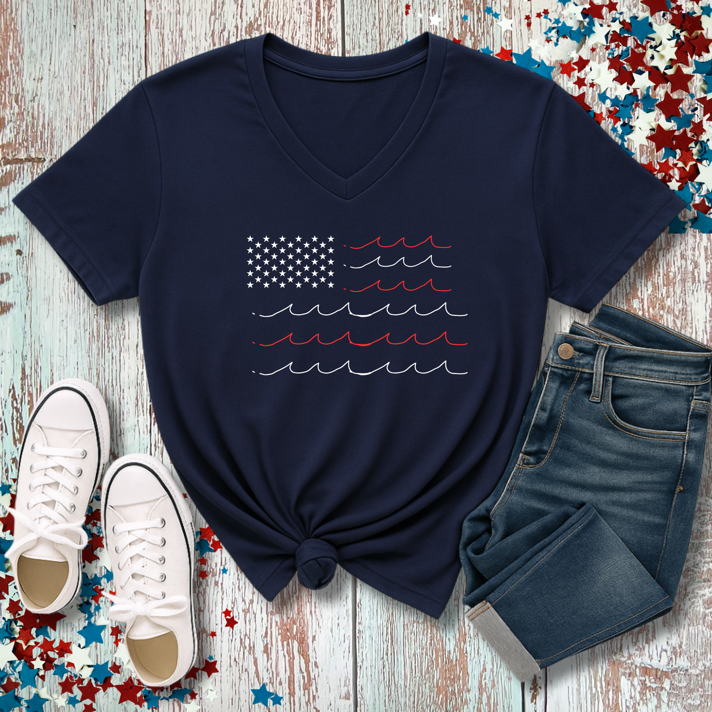 Navy blue t-shirt with a palm tree design, white sneakers, and denim shorts on a wooden surface with a colorful star pattern.