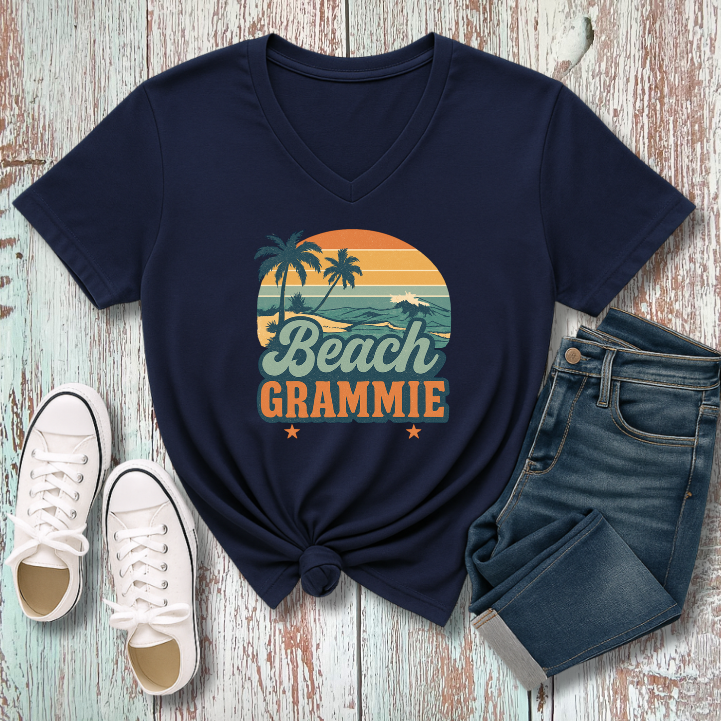 Navy blue t-shirt with 'Beach Grammie' design on a wooden surface with white sneakers and jeans.