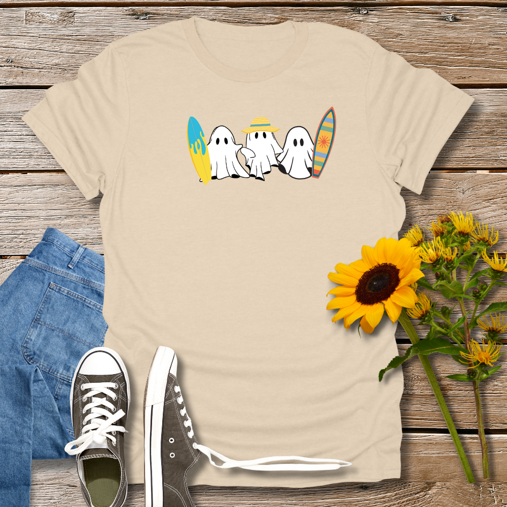 Beige t-shirt with ghost design, blue jeans, black sneakers, and sunflowers on a wooden surface