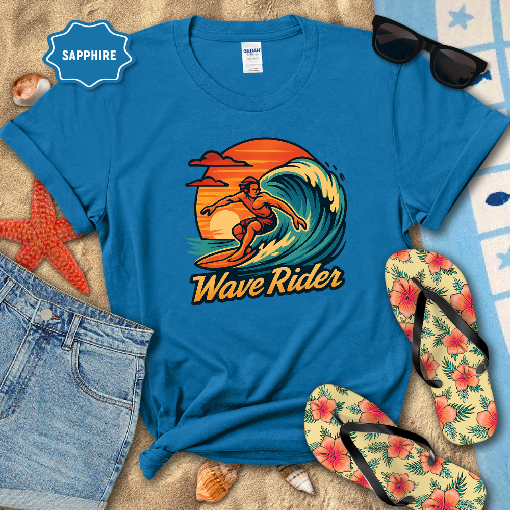 Blue t-shirt with 'Wave Rider' design on a sandy surface with sunglasses, flip-flops, and denim shorts.