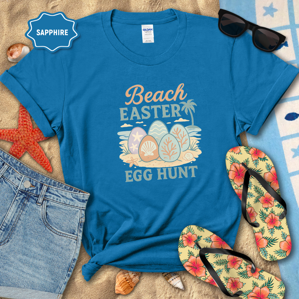Blue t-shirt with 'Beach Easter Egg Hunt' design on a sandy background with flip-flops and sunglasses.