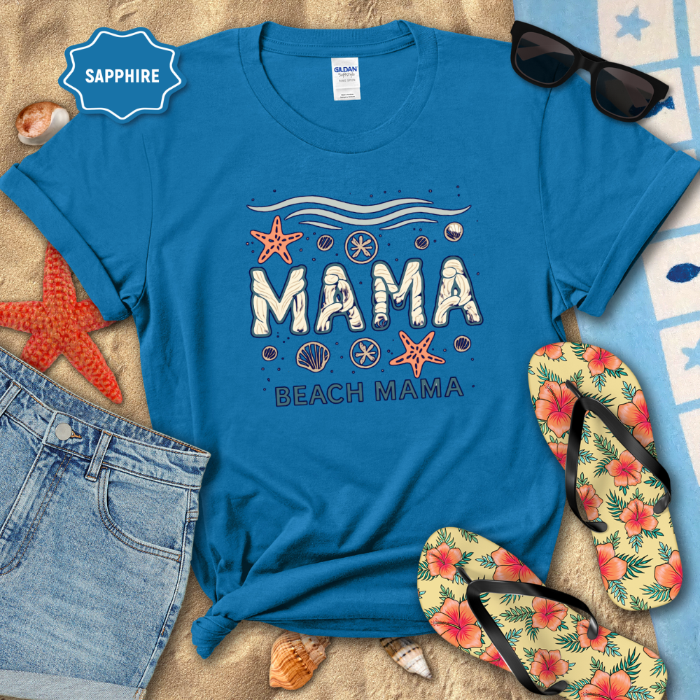 Blue t-shirt with 'Mama Beach Mama' design on a sandy background with sunglasses, flip-flops, and beach accessories.
