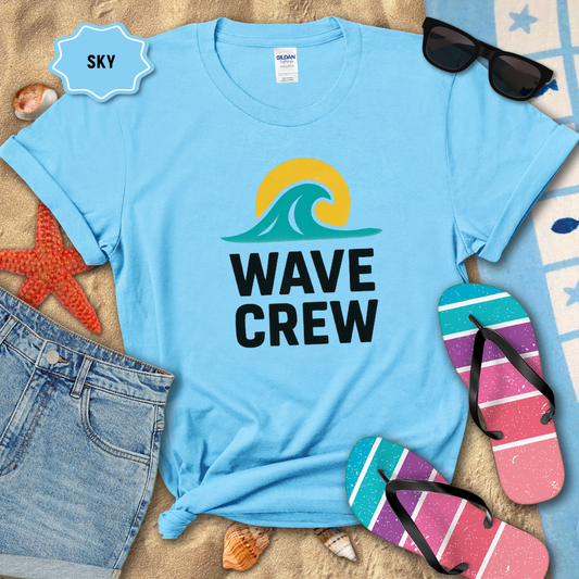 Light blue t-shirt with 'WAVE CREW' design on a sandy background with beach accessories.