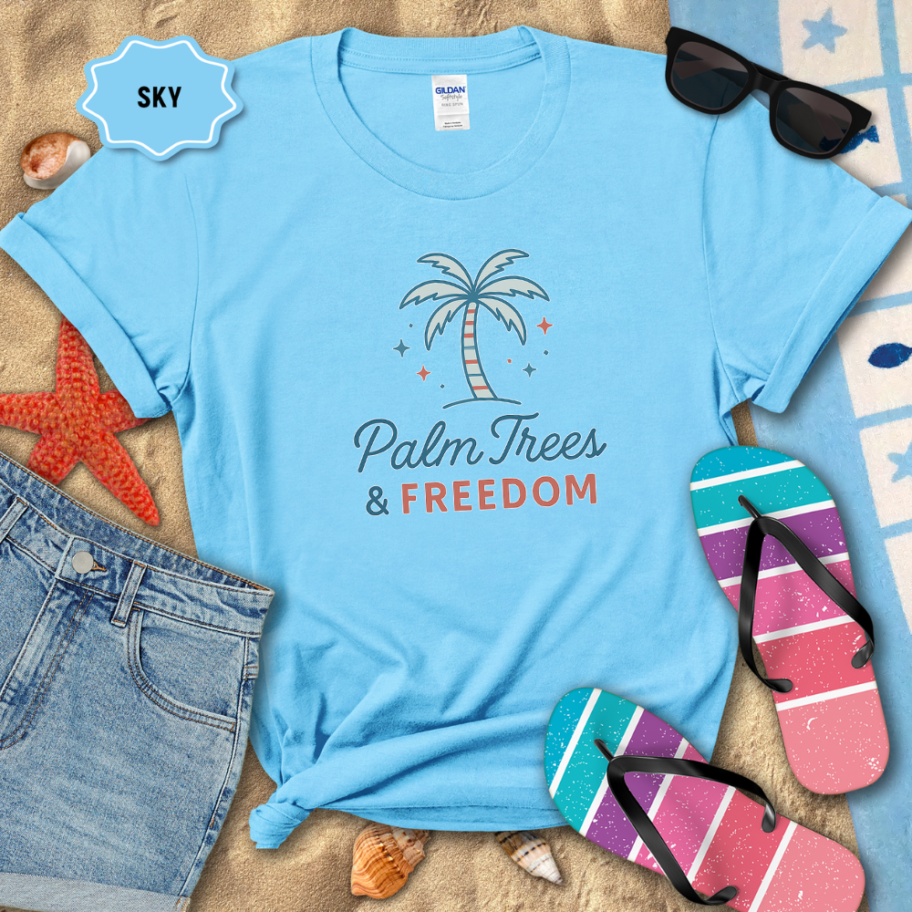 Blue t-shirt with 'Palm Trees & Freedom' design on a sandy background with beach accessories.