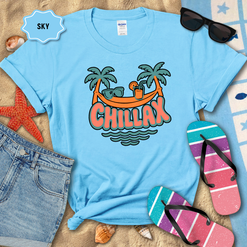 Blue t-shirt with 'Chillax' design on a sandy background with beach accessories.