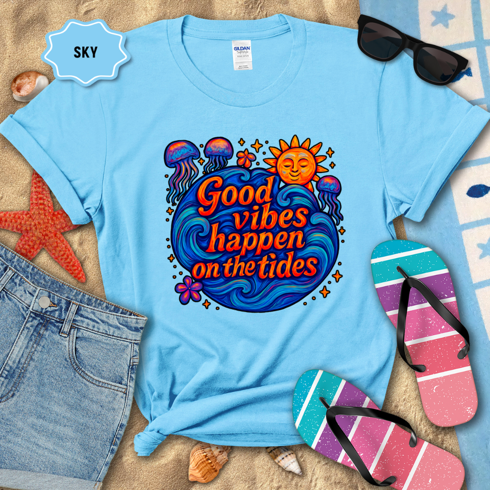 Light blue t-shirt with 'Good vibes happen on the tides' design, surrounded by beach accessories.