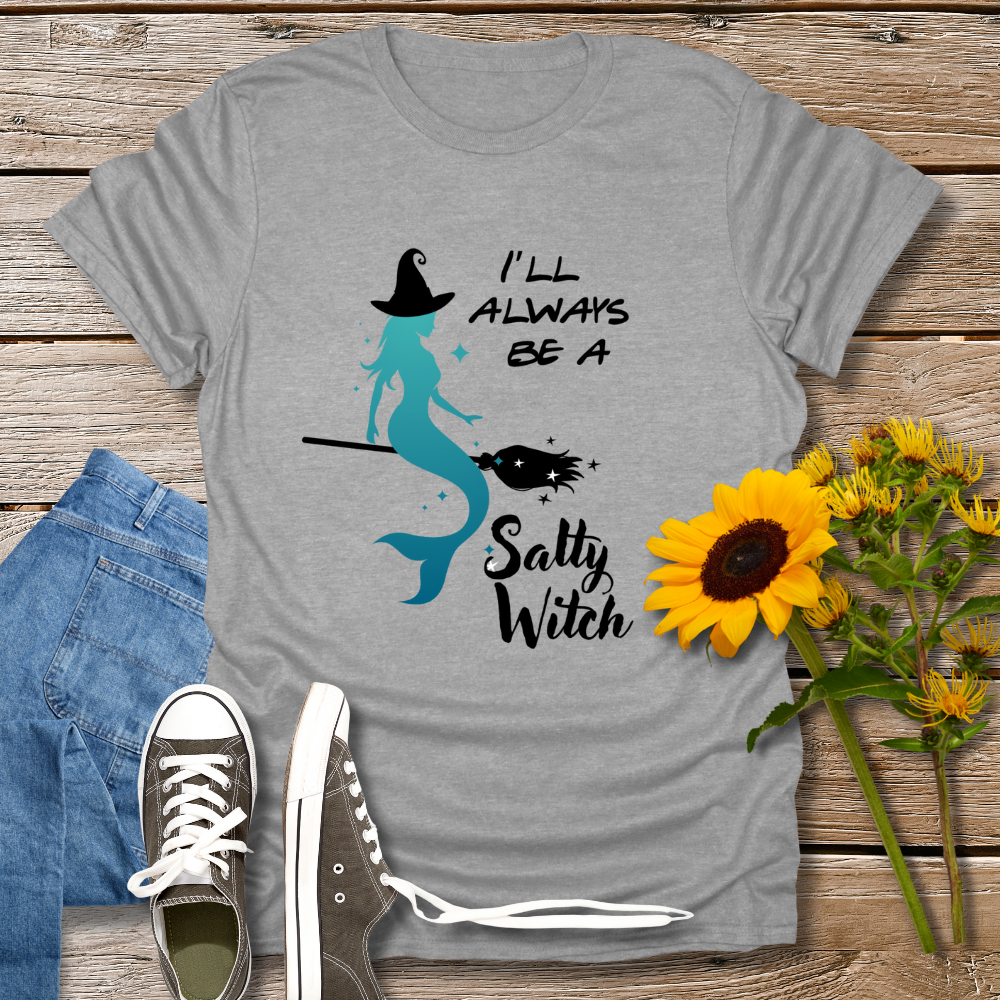 Gray t-shirt with mermaid graphic and text on a wooden surface with jeans and sunflowers.
