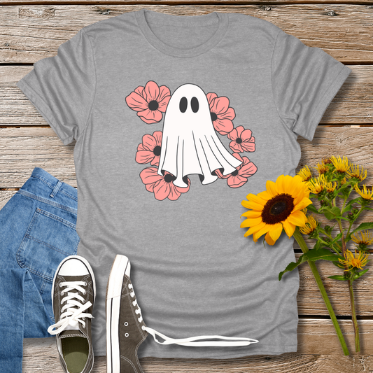 Gray t-shirt with ghost and flower design on a wooden surface with jeans and sneakers.