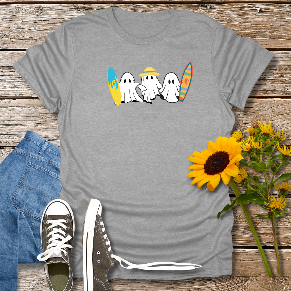 Gray t-shirt with ghost design, jeans, sneakers, and sunflowers on a wooden surface