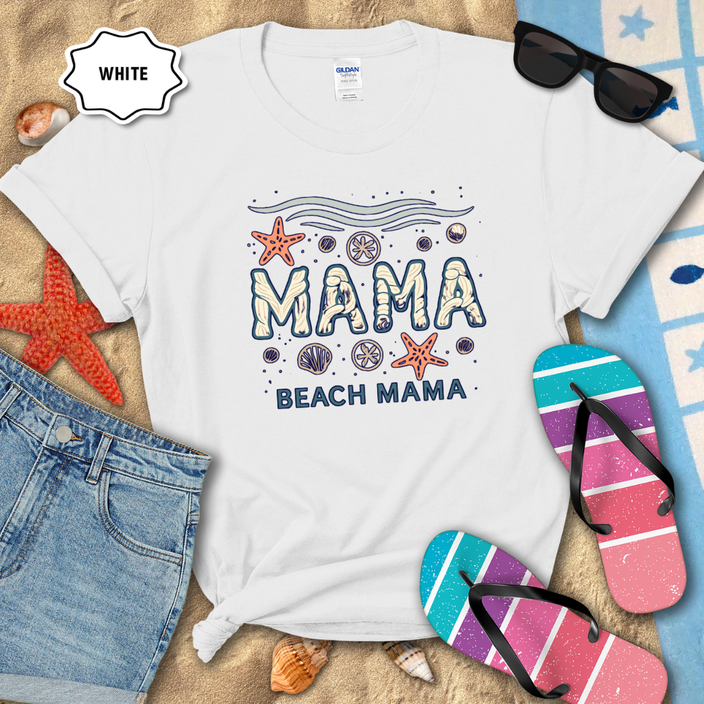 White t-shirt with 'Beach Mama' design on sand with flip-flops and sunglasses.