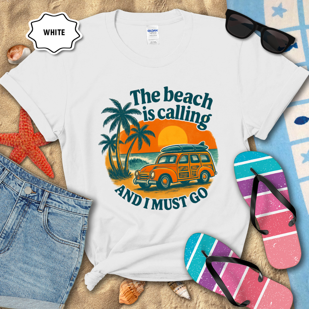 White t-shirt with beach-themed design featuring a van, palm trees, and text on a sandy background.