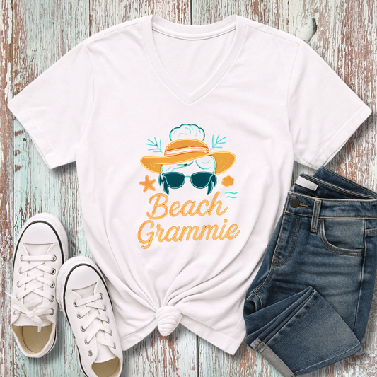 White t-shirt with 'Beach Grammie' design, white sneakers, and denim shorts on a wooden surface